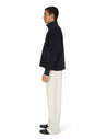 Person wearing a black sweater and white pants on a white background