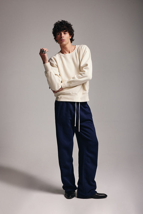 Les Tien quiet fashion leisure wear made for him, mens collection, image of man standing wearing navy pants and ivory long sleeve 