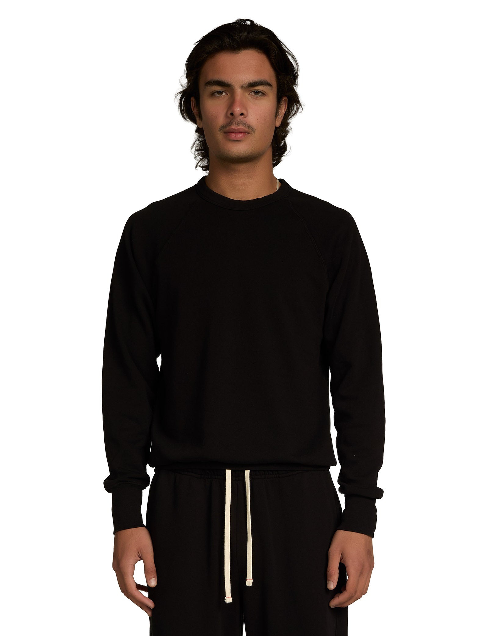 Person wearing a black long-sleeve shirt and black pants with a white drawstring on a white background