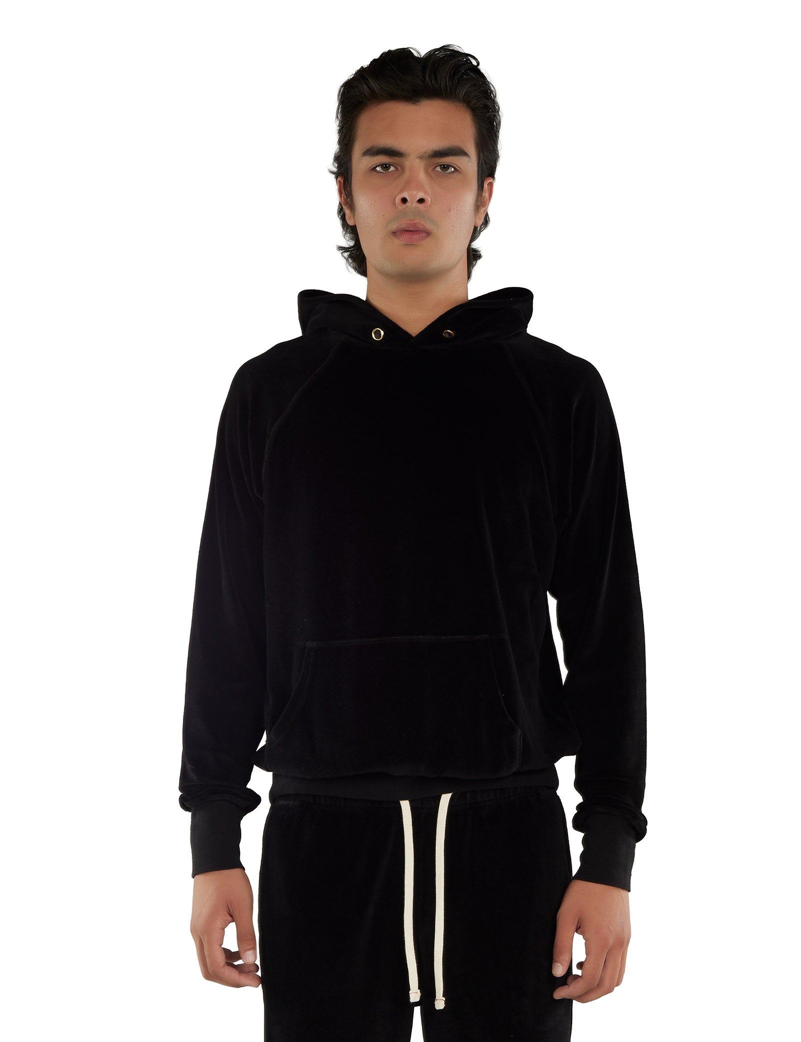 Person wearing a black velour hoodie with gold eyelets and black pants with white drawstrings on a white background